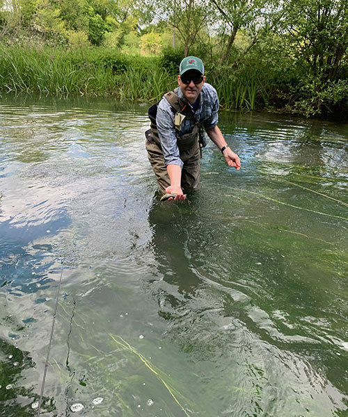 Man fishing by The Bull Hotel on River Coln